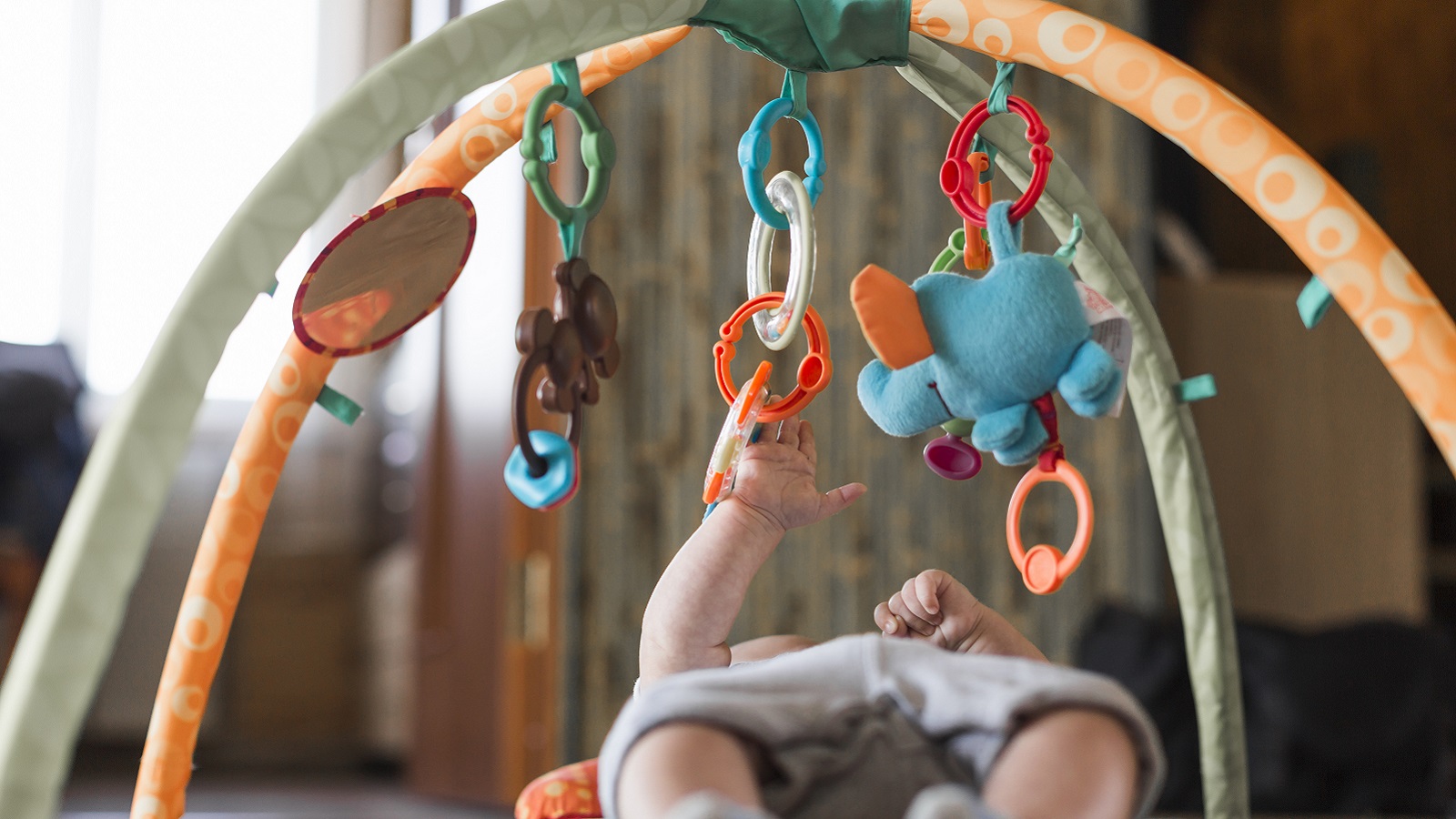 baby lying developing rug with mobile educational toys